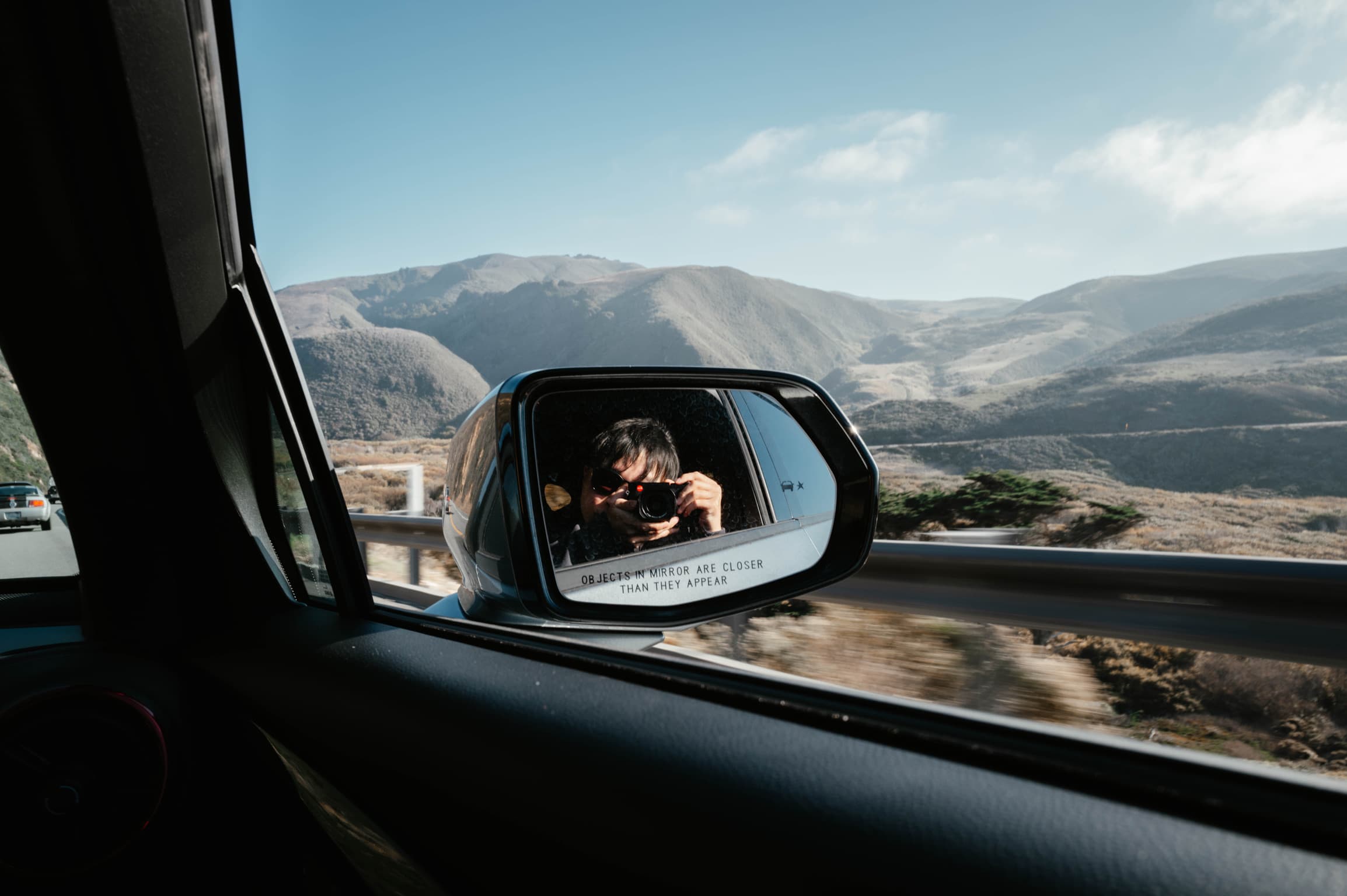 Photo of Big Sur landscape from car side mirror reflection
